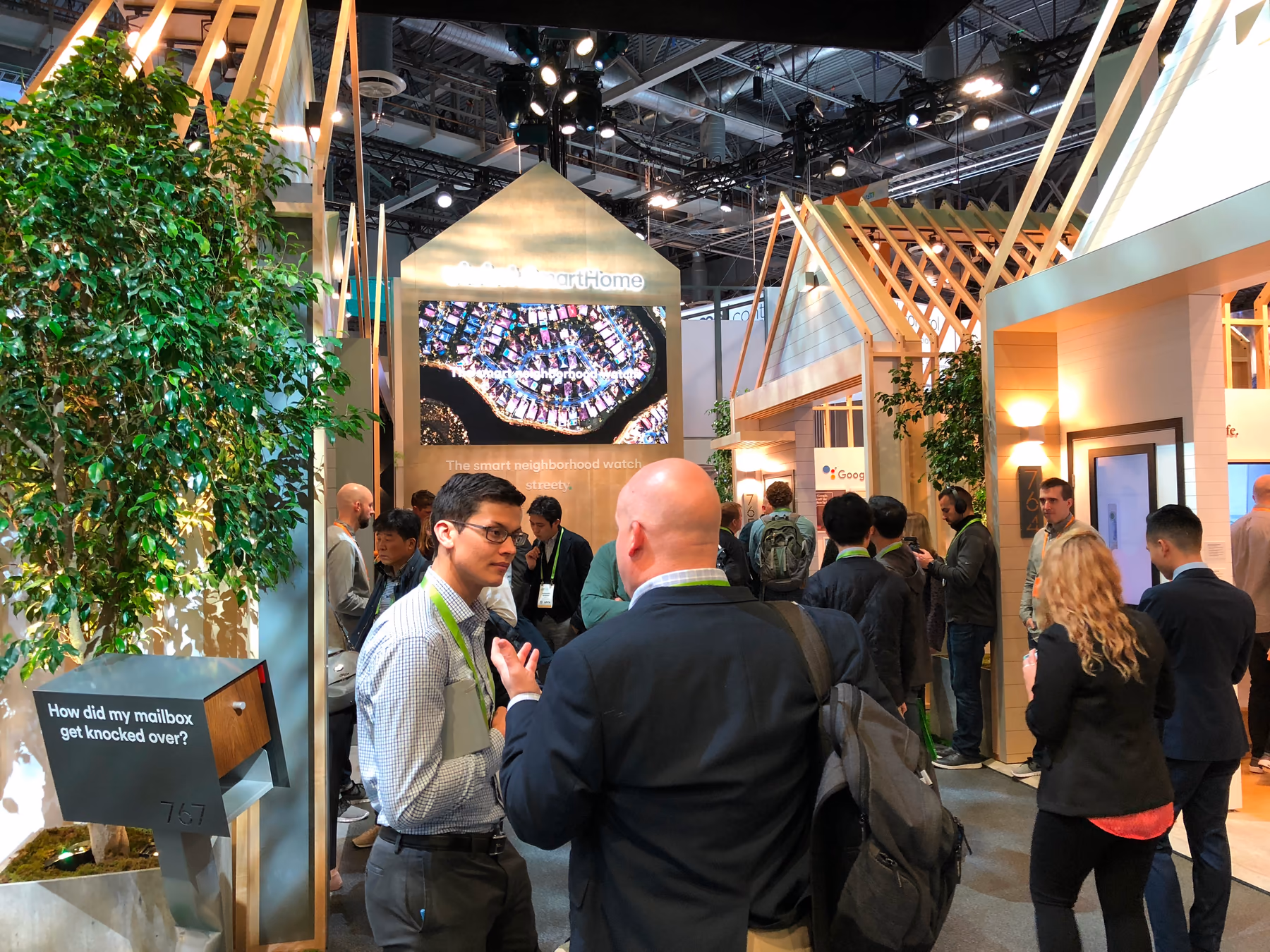 The Vivint CES booth built as a neighborhood street, with framed houses, a mailbox posing a Streety request, and a screen reading The smart neighborhood watch